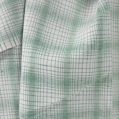 White linen cotton fabric with striped green checks close up view of pattern