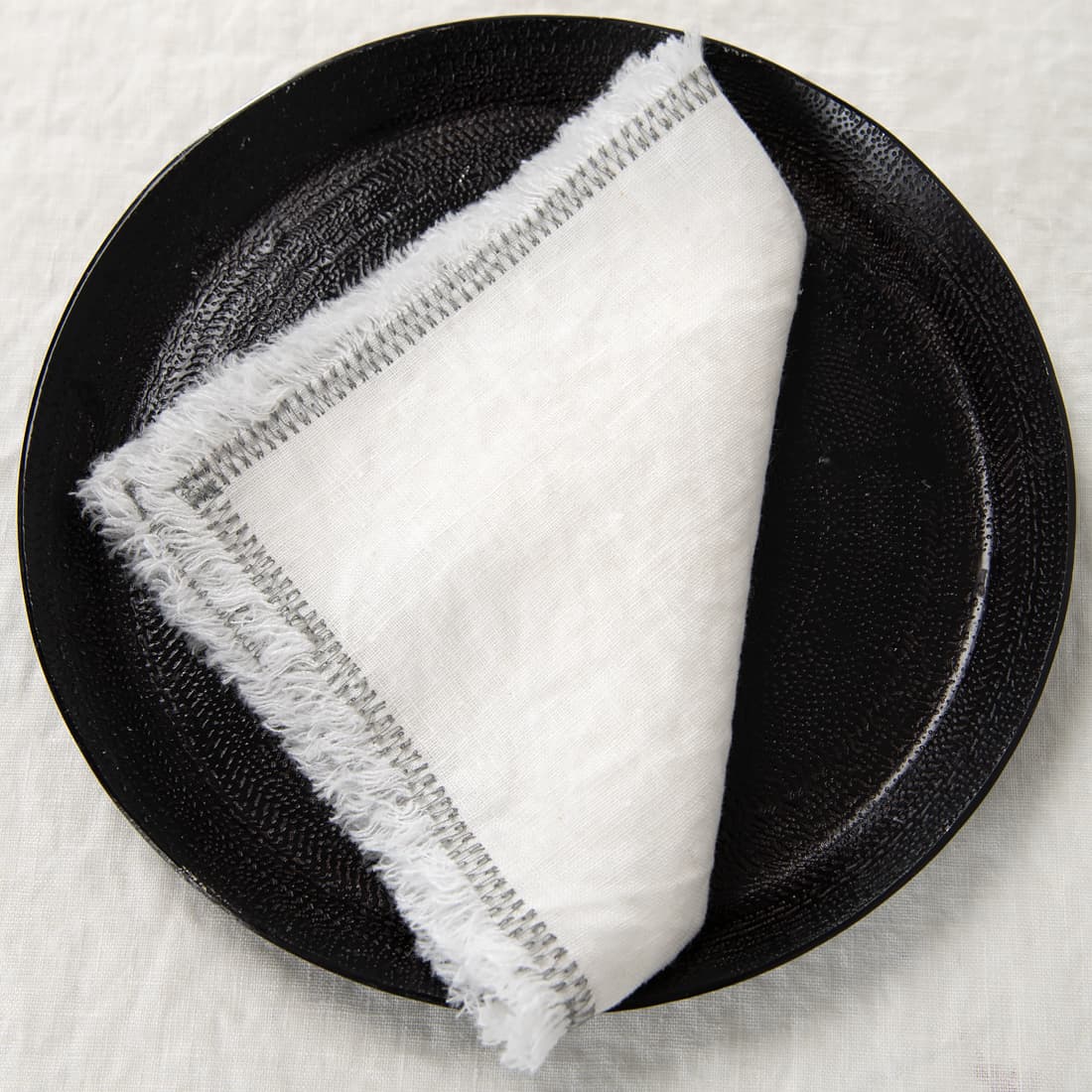white linen napkin with decorative stitch.