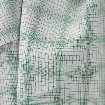 White linen cotton fabric with striped green checks close up view of pattern