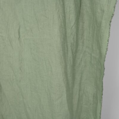 Washed linen fabric in muted light green, fabric edge