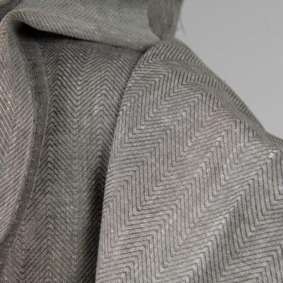 Linen fabric greyish brown in herringbone pattern close up detail